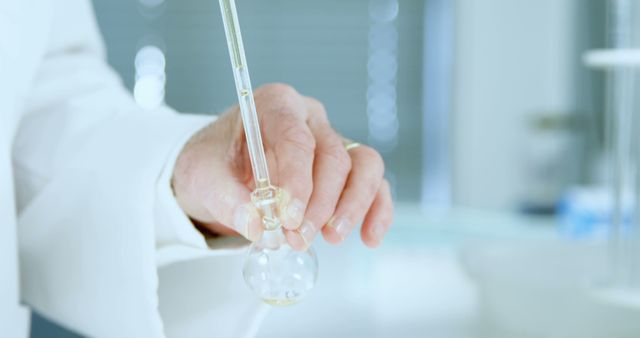 Scientist holding a dropper while conducting an experiment in a laboratory setting. Perfect for use in medical or scientific articles, educational materials, or promotional content for laboratory supplies and research organizations.