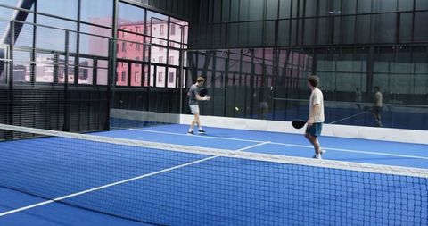 Two Men Playing Padel in Modern Indoor Court
