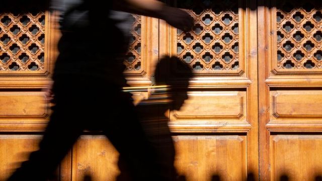 Walking silhouette casting child profile shadow on ornate carved wooden door, urban street