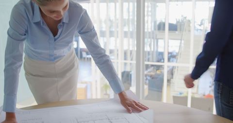 Businesswoman analyzing project plans in modern office workspace