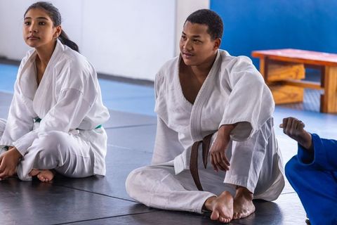 Diverse martial arts students wearing judo gis preparing for training