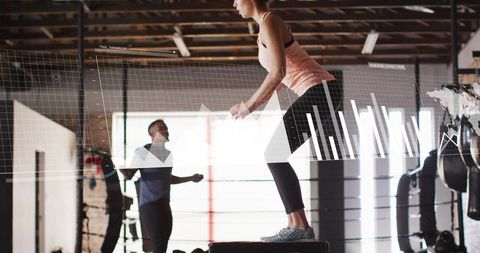 Female athlete performing plyometric box jump with fitness hud overlay in loft gym