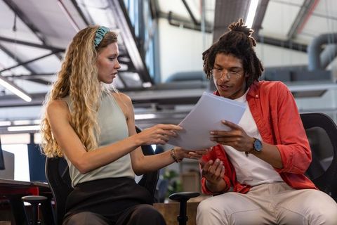 Diverse coworkers reviewing documents in open-plan office