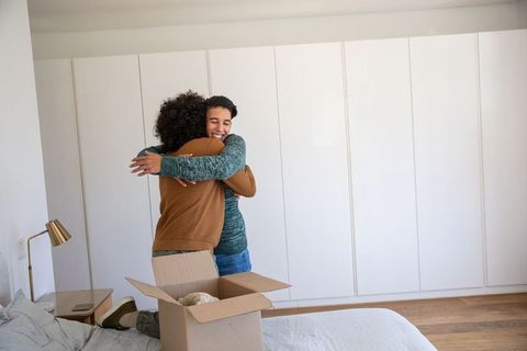 Happy Couple Embracing Near Moving Box in Bedroom