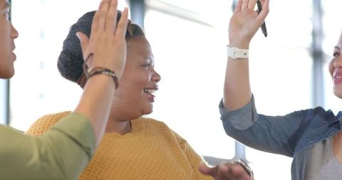 Diverse team celebrating success with high five featuring African American woman in office