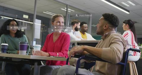 Diverse office team collaborating in breakout space, inclusive coworker in wheelchair