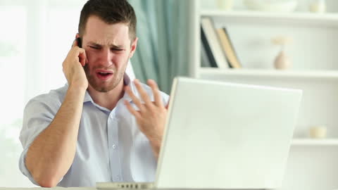 Stressed Man on Phone Call at Home Workspace