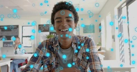 Smiling student leaning on desk showing blue hex digital overlay for edtech learning