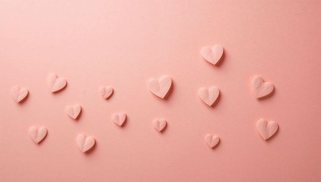 Scattering pink paper hearts casting soft shadows on pastel cardstock background