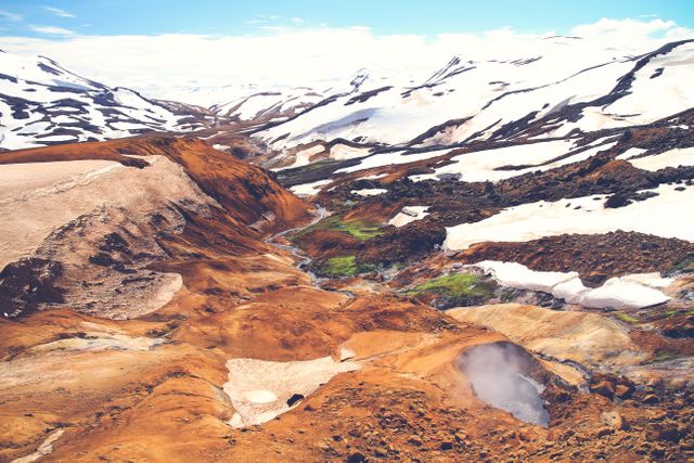 This image showcases a beautiful contrast of snow and geothermal activity in a mountainous region, perfect for travel blogs or outdoor adventure promotions.