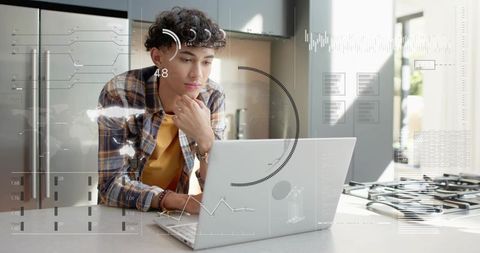 Young man working on laptop at kitchen island with futuristic hud overlay, remote work