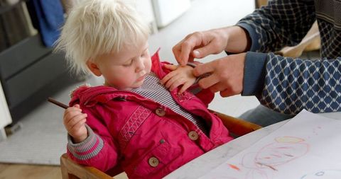 Father helping daughter remove jacket at home