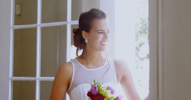 Smiling Bride Holding Bouquet Next to Sunlit Window - Download Free Stock Images Pikwizard.com