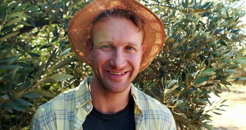 Smiling Man in Sunny Orchard with Hat Enjoying Nature