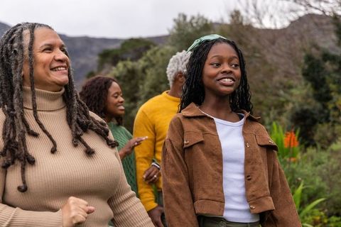 Multigenerational african american family walking and smiling on green hills