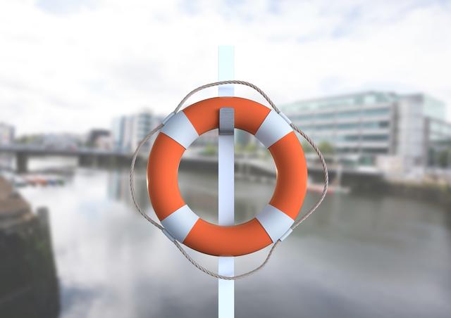 Vibrant lifebuoy hanging on pole in foreground with blurred urban waterfront cityscape in background. Useful for illustrating themes of safety and rescue in marine or urban environments. Perfect for promotional materials, educational content, and safety guidance related to water and boating activities.