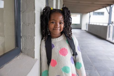 Confident young girl standing in school hallway