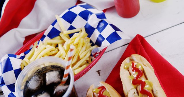 Hotdogs topped with mustard and ketchup, served with golden french fries and soda in a red basket. Perfect for representing American cuisine, fast food, picnics, outdoor events, food promotions, and diner menus.