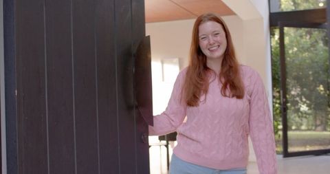 Smiling woman welcoming at home entrance with open door