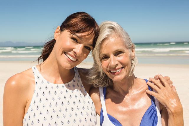 Portrait of smiling mother and daughter standing against clear sky at beach