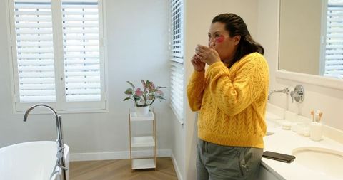 Mature woman enjoying morning coffee in bathroom