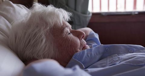 Elderly woman relaxing comfortably in her bed