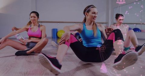 Women performing core stretching in studio, blue-tank woman leading group fitness session