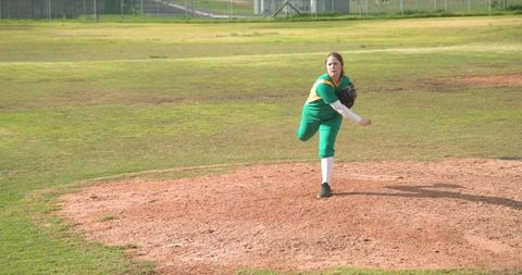 Focused female softball pitcher on mound during game