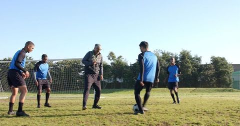Diverse Soccer Team Training on Field with Coach