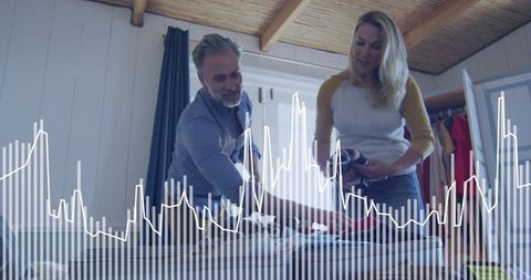 Couple packing and organizing luggage with analytics overlay in cozy rustic loft bedroom
