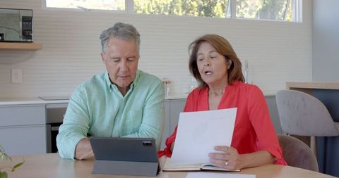 Senior couple reviewing finances with tablet at home