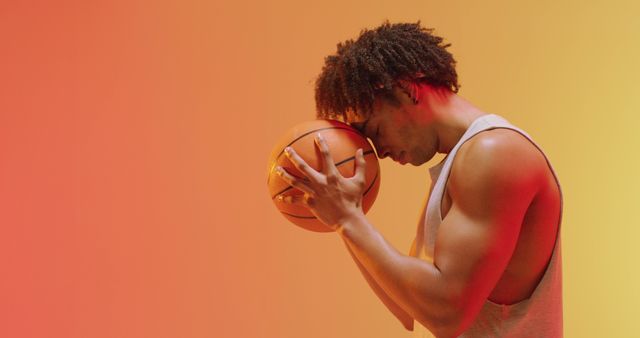Image of biracial male basketball player with ball on orange to yellow background. Sports and competition concept.