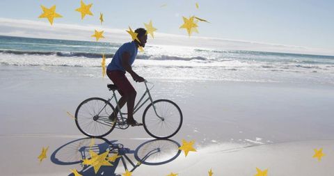 Riding bicycle along sunlit shoreline with reflection and playful yellow star overlays