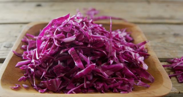 A wooden bowl is filled with freshly chopped red cabbage, ready for use in a variety of healthy dishes. Red cabbage is known for its vibrant color and is a nutritious addition to salads, slaws, and cooked meals.