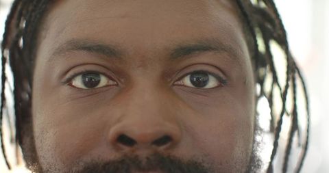 African man looking forward with beard and dreadlocks closeup headshot eyes natural light