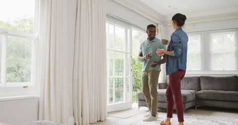 Happy Diverse Couple Dancing in Cozy Living Room