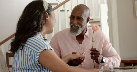 Senior couple sharing romantic moment with rose at home