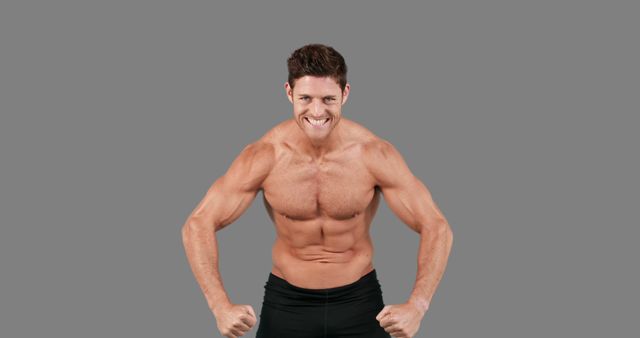 A muscular Caucasian man flexes his biceps and smiles confidently, with copy space. His physique showcases dedication to fitness and strength training.