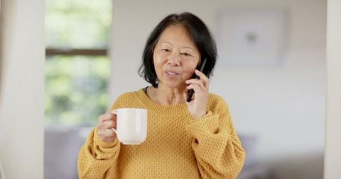 Senior Woman in Cozy Sweater Relaxed at Home Talking on Phone