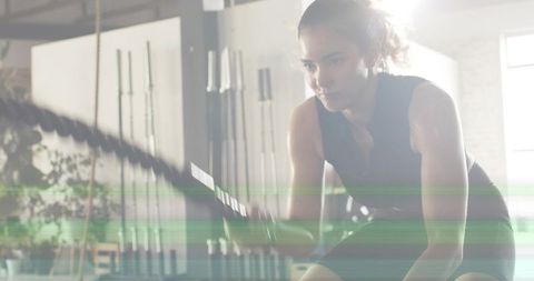 Female athlete swinging battle ropes during intense gym strength and conditioning