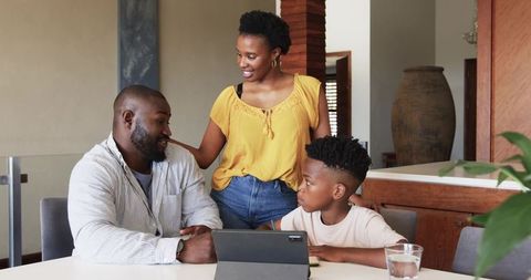 African American family sharing warm kitchen moment with child using tablet