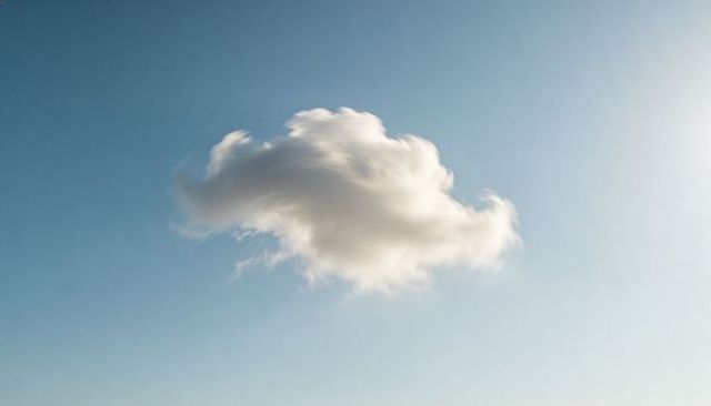 Solitary Cumulus Cloud Drifting Across Clear Blue Sky with Soft Sun Glare and Minimalist Mood