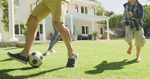 Family Playing Soccer Together on Sunny Day in Backyard