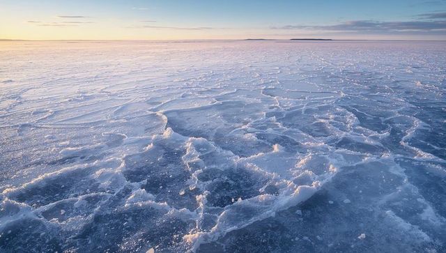 Sunrise illuminating textured sea ice field with frost ridges and pastel arctic sky