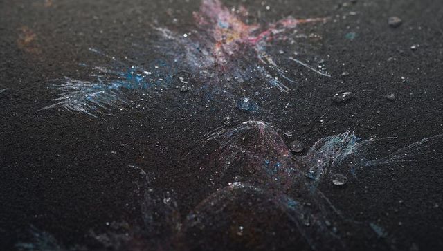 Iridescent pigment splatter with water droplets on dark matte surface macro texture