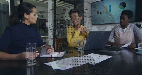 Collaborating women reviewing sales charts and strategy on laptop and tablet in boardroom