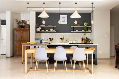 Contemporary kitchen featuring wooden dining table, gray chairs, marble backsplash