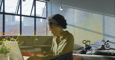 Professional woman typing on laptop with data graphs overlay in modern coworking space