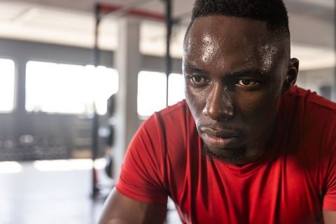 African american athlete pushing through indoor cycling session, sweating and determined