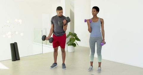 Diverse Exercise Partners Lifting Dumbbells in Home Workout Space